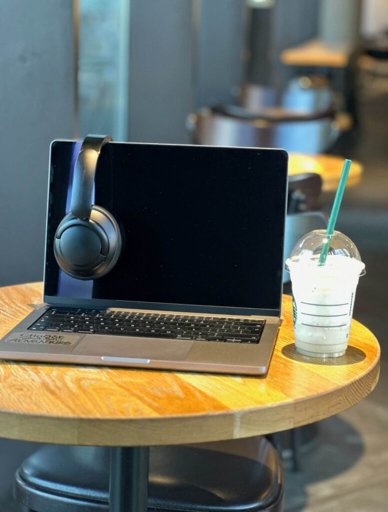 Laptop on small table with headphones and cup of water