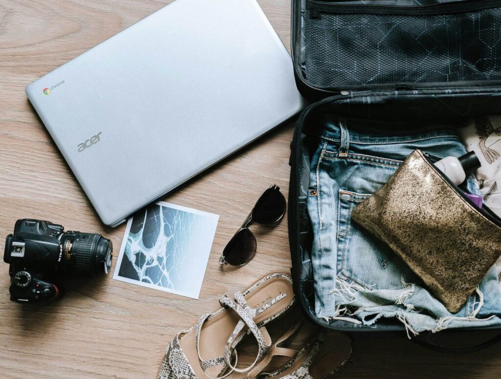 Open suitcase with clothes and purse, with accessories next to it