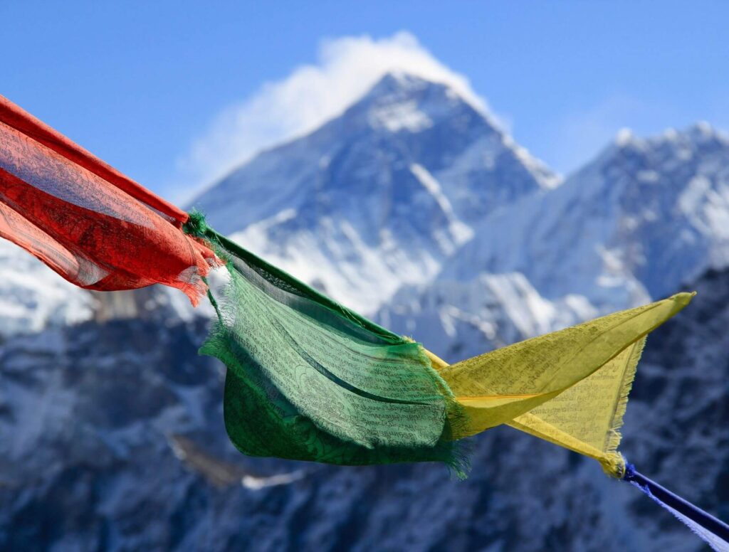 colorful flags fly with Everest in the background