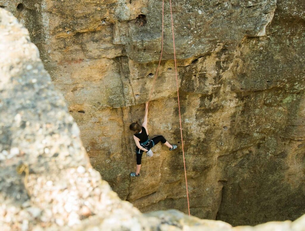 female climbing a vertical cliff