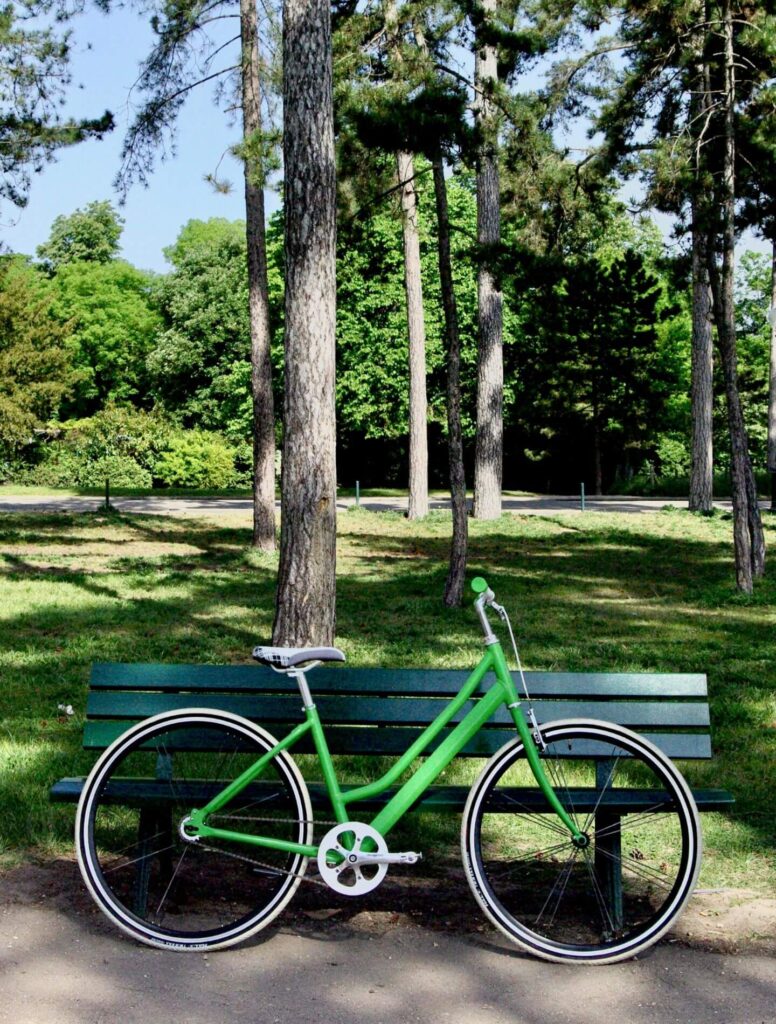 Green bike leaning on park bench