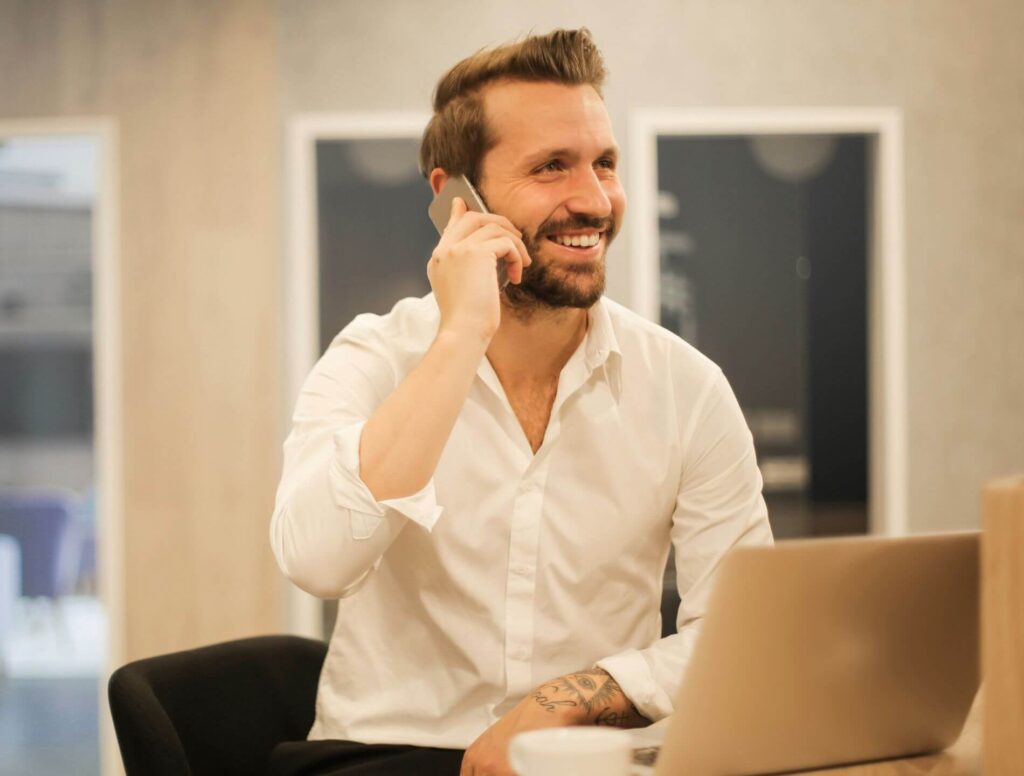 Man talking on his cell phone sitting in front of his laptop
