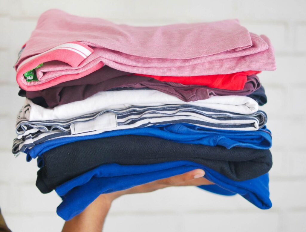 person holding a stack of folded shirts