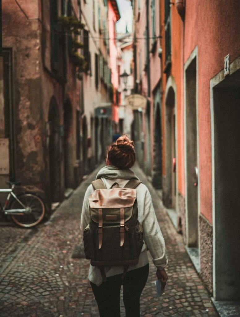 Woman walking through alley wearing a jacket and backpack