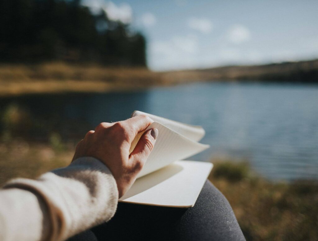 person journaling by a lake