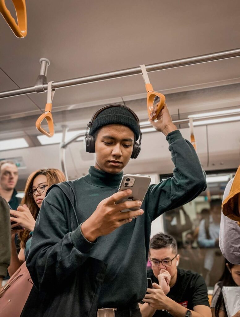 man standing in crowded train using his cell phone