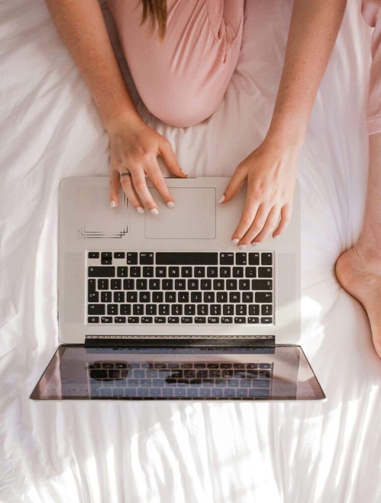 Woman working on laptop from her bed