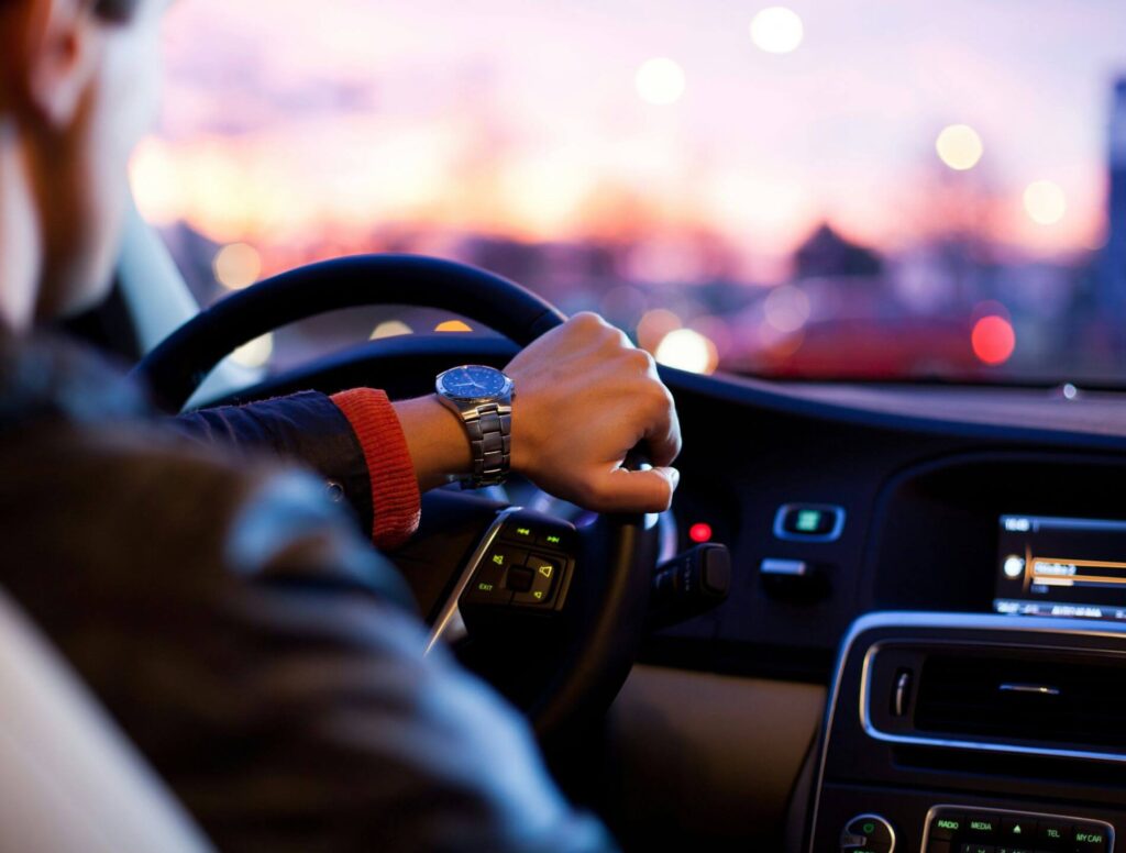Man with hand on car steering wheel