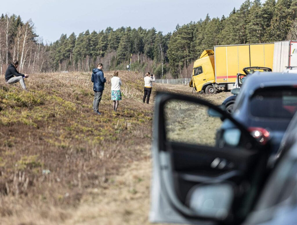 People standing on the side of a highway after a truck accident.